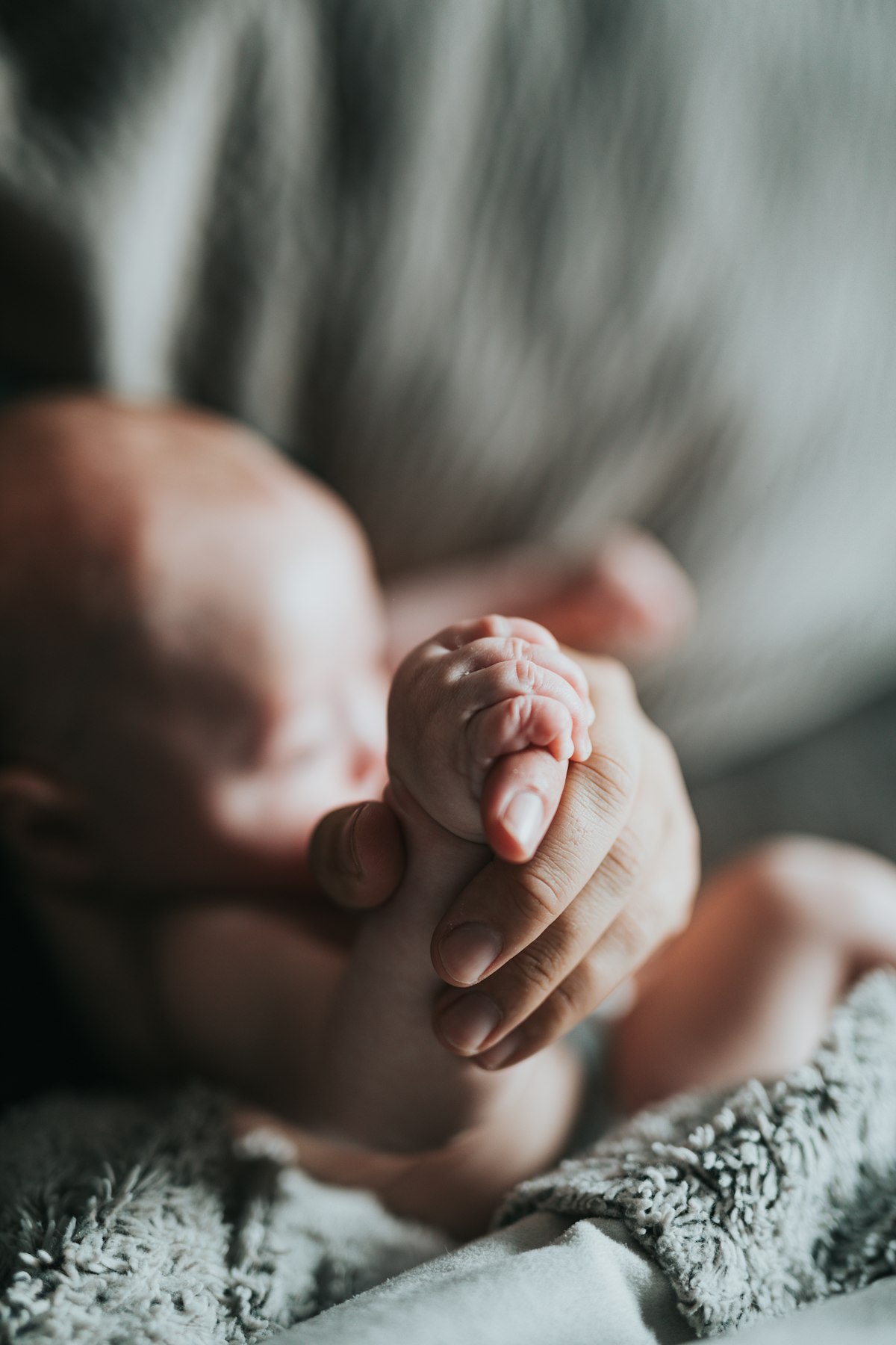 A parent gently holding their newborn baby's hand